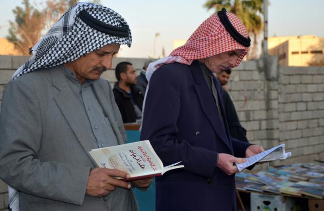 Des Irakiens feuillettent des livres dans une rue de Mossoul (nord), six mois après sa libération des jihadistes, le 12 janvier 2018 [Ahmad MUWAFAQ / AFP]