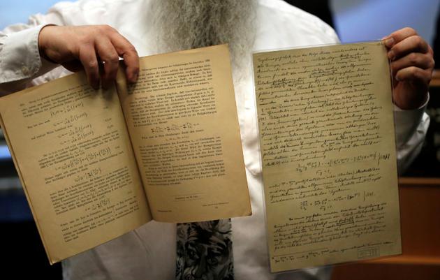 Le docteur Roni Grosz montre des documents originaux écrits par Albert Einstein, et prédisant la découverte future d'ondes gravitationnelles, à Jérusalem, le 11 février 2016 [THOMAS COEX / AFP]