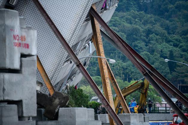 La tour Yun Tsui, gravement endommagée après le séisme et penchant à un angle précaire, est soutenue par des poutres métalliques, le 8 février 2018  à Hualien à Taïwan  [Anthony WALLACE / AFP]
