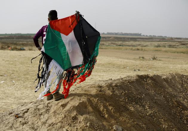 Un jeune Palestinien tient un cerf-volant aux couleurs palestiniennes près de la frontière entre la bande de Gaza et Israël, 20 avril 2018 [MOHAMMED ABED / AFP]