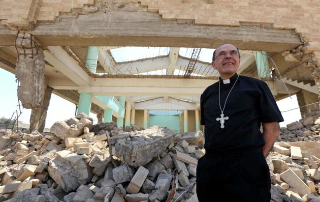 Le cardinal Philippe Barbarin marche parmi les ruines de l'église assyrienne des Martyrs ne reste plus que des murs défoncés, à Mossoul le 25 juillet 2017 [SAFIN HAMED / AFP]