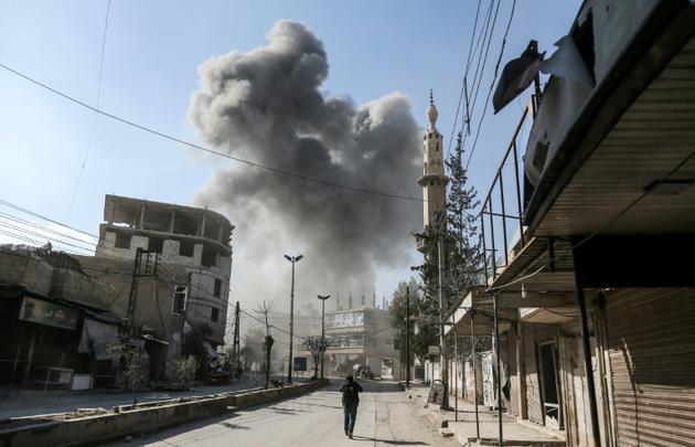 De la fumée s'élève au-dessus d'un bâtiment après des bombardements sur la ville de Hamouria, dans l'enclave rebelle de la Ghouta orientale, près de Damas le 21 février 2018 [ABDULMONAM EASSA / AFP]