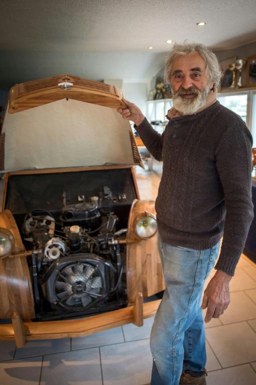 Le 21 mars 2017 à Loches, Michel Robillard soulève le capot en pommier de sa 2CV en bois pour montrer le moteur de 3CVqu'il a installé [GUILLAUME SOUVANT / AFP/Archives]