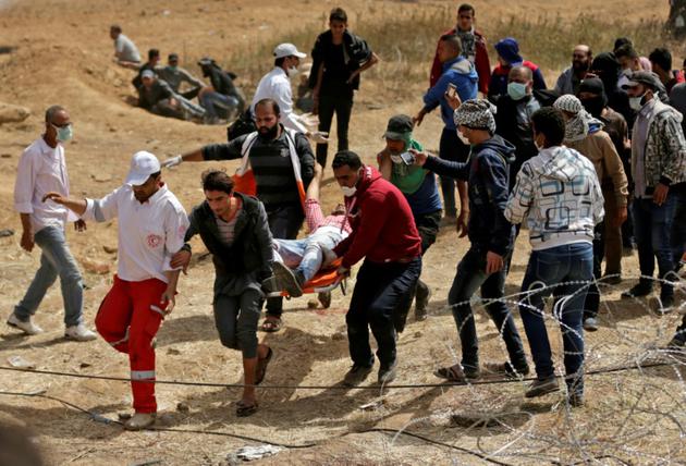 Evacuation d'un manifestant palestinien blessé par les forces de sécurité israéliennes près de la frontière entre Gaza et l'Etat hébreu, le 13 avril 2018 [MAHMUD HAMS / AFP]