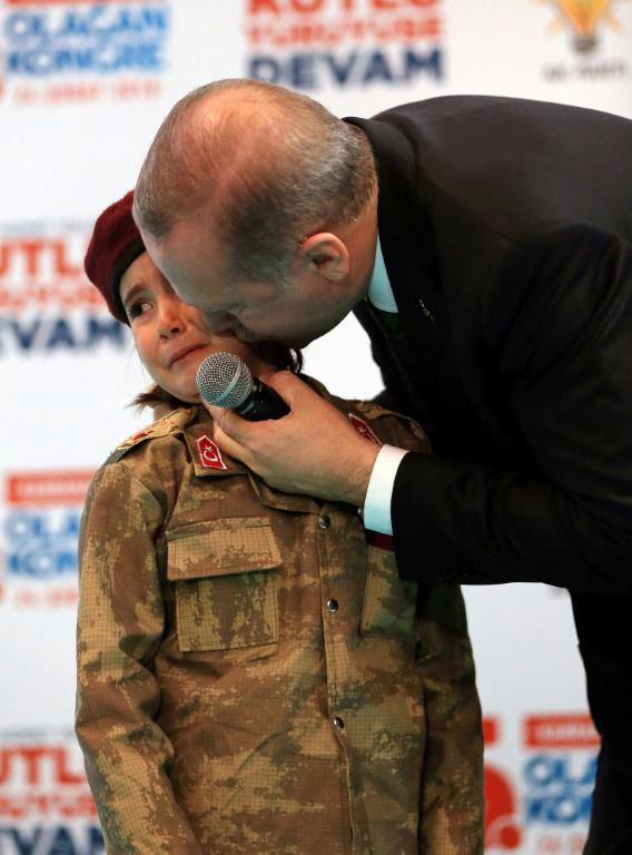 Cette photo, prise le 24 février 2018 et publiée le 28 février 2018 par le service de presse présidentiel turc, montre Recep Tayyip Erdogan embrassant Amine Tiras, une petite fille de 6 ans en treillis militaire, à Kahramanmaras [Handout / TURKISH PRESIDENTIAL PRESS SERVICE/AFP]