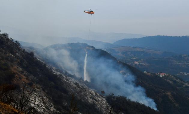Un hélicoptère lâche de l'eau sur les collines de Toro Canyon, au nord de Santa Barbara, en Californie, le 12 décembre 2017 [FREDERIC J. BROWN / AFP]
