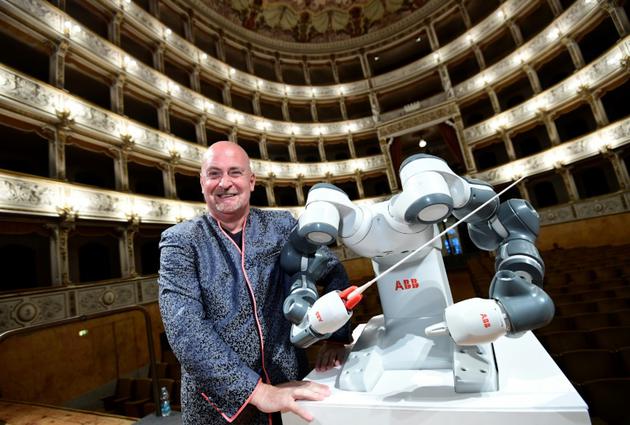 Le chef de l'orchestre philharmonique de Lucca, Andrea Colombini aux côtés de YuMi le robot, le 12 septembre 2017 à Pise [MIGUEL MEDINA / AFP]